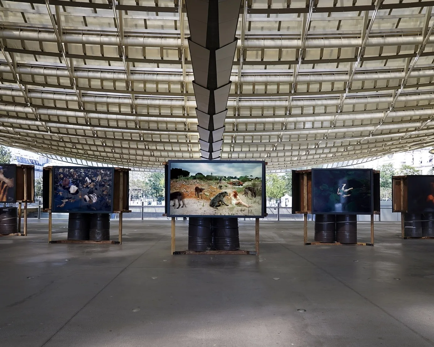 Grands tirages posés sur des fûts métalliques sous la toiture ajourée de la Canopée du Forum des Halles, à Paris.