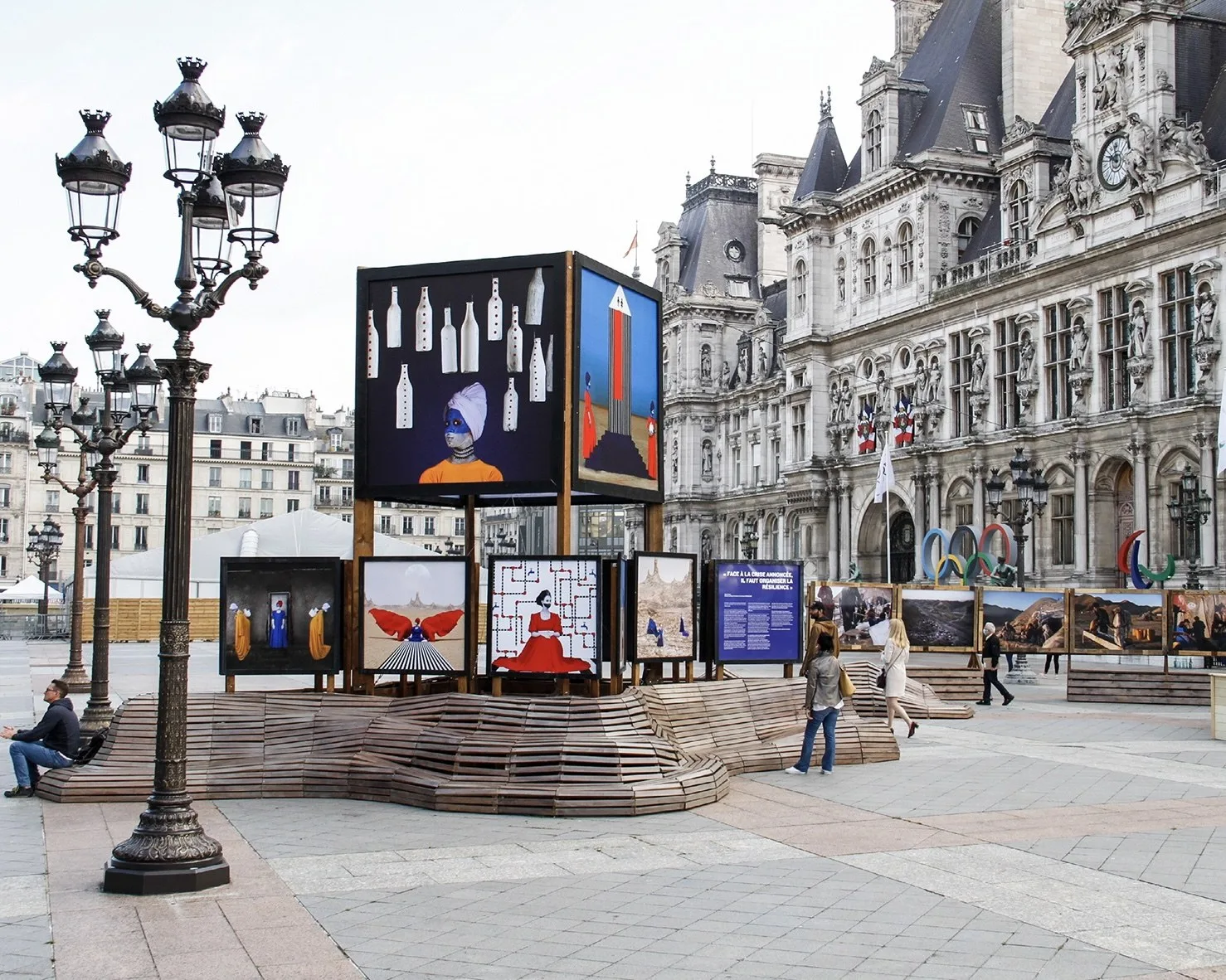 Œuvres d'Aïda Muluneh sur un cube et des panneaux, au-dessus de gradins en bois ondulés, devant la façade de l'Hôtel de Ville de Paris.