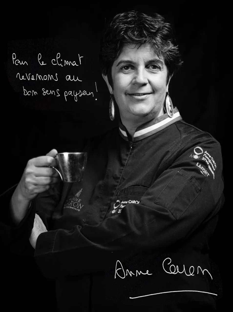 Portrait noir et blanc d'Anne Caron en veste de cuisine, une tasse à la main, avec le message « Pour le climat revenons au bon sens paysan ! ».