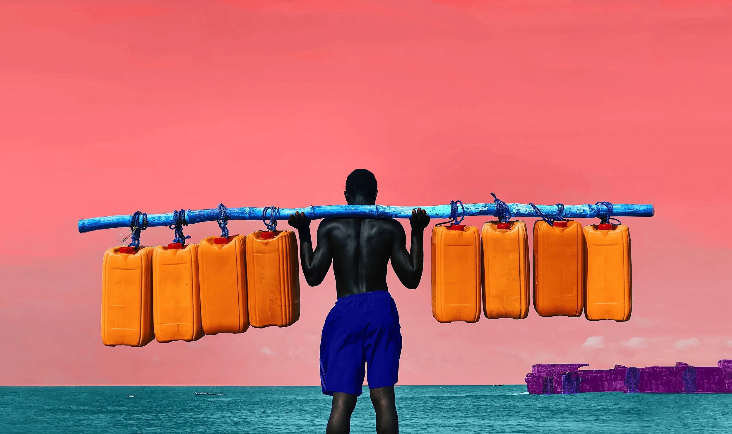 Un homme de dos face à la mer porte sur ses épaules une perche bleue d'où pendent des bidons jaunes, sous un ciel rose.